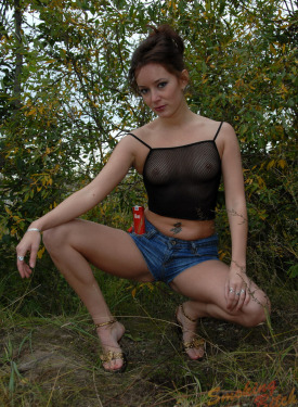 Girl with puffy nipple under net top dressed in tight blue jeans shorts is smoking outdoor
